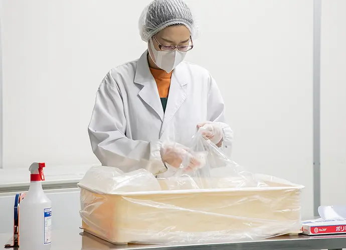 白衣を着た女性が料理の準備をしています。