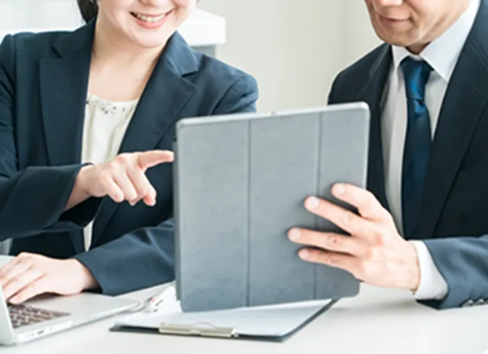 タブレットを見ながら話し合う二人のビジネスパーソン。