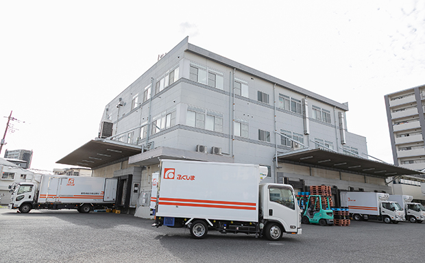 大きな白い建物の前に数台のトラックが駐車されています