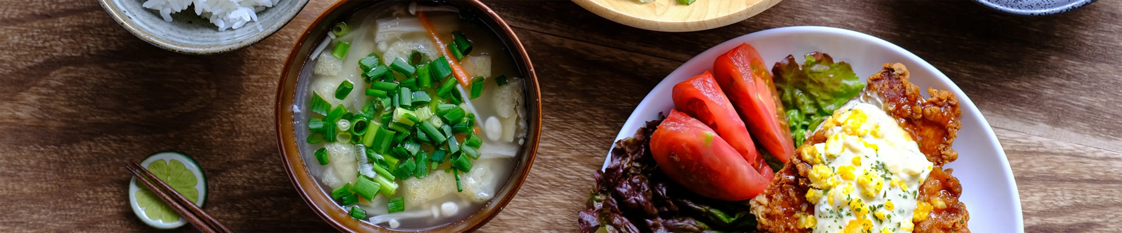 テーブルの上にスープ、米、野菜のボウルが置かれています。